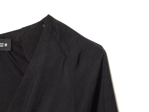 Close-up detail of a black V-neck top showing textured woven fabric and neckline stitching