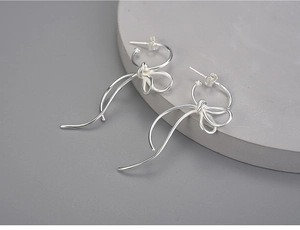 Detailed close-up of S925 sterling silver bow earrings with polished finish on grey background