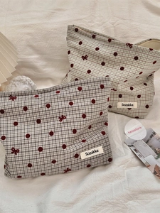 Plaid canvas makeup bags with red polka dots and bow patterns in a stacked display