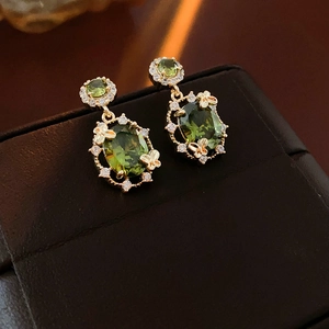 Macro di orecchini vintage dorati con pietra verde ovale e dettagli di farfalla in zircone