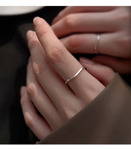 Close-up of minimalist S925 sterling silver wavy ring on finger with soft focus background