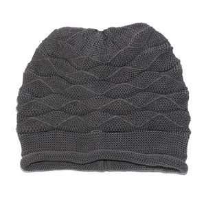 Close-up of dark grey knitted beanie showing thick wavy texture and rolled cuff detail