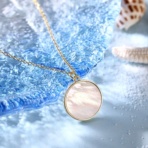 Macro shot of S925 silver necklace with white shell pendant on blue glass beach decor