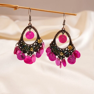 Macro view of vintage bohemian dangle earrings with magenta beads on wood branch