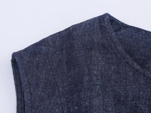 Gros plan détaillé sur la texture du denim et les doubles coutures à l'épaule de la robe