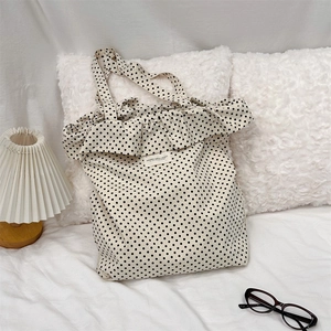Polka dot canvas tote bag with ruffled edges shown in a cozy lifestyle bedroom setting