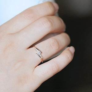 Exquisite twisted crossover ring in rose gold with a round center stone and micro diamonds