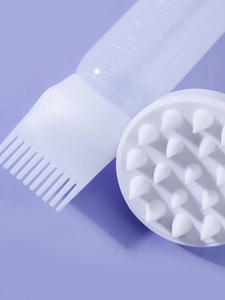 Close-up of hair oil applicator bottle with scale markings and silicone scalp massage brush