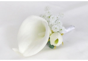 Detail of white calla lily boutonniere with silk ribbons and secure pin for weddings