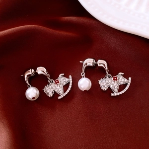 Détail de boucles d'oreilles cheval à bascule avec cristaux, émail rouge et perle blanche