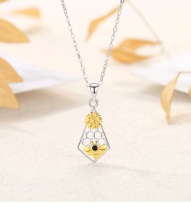Detail of silver honeycomb necklace with golden bee and sunflower on autumn background