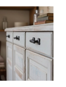 Detail of vintage cast iron drawer handles in black on ivory white cabinet doors