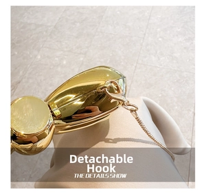 Detail showing the shiny gold gourd clutch with a detachable metal chain hook
