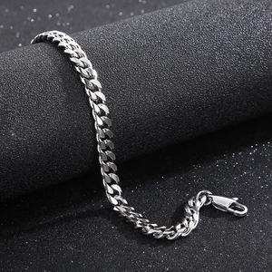 Close-up of polished silver titanium steel curb link bracelet on black textured surface