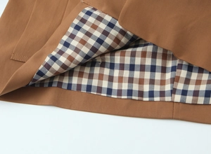 Detail view of khaki trench coat hem with plaid lining and high-quality stitching