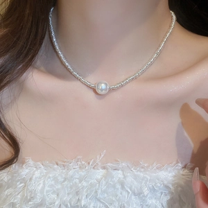 Detailed close-up of a silver textured choker necklace with a central round pearl pendant