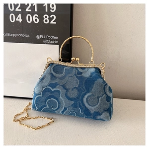 Detail of denim handbag featuring floral patterns, gold metal clasp and rhinestone trim