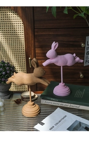 Dettaglio di statuette di coniglio nordico in resina rosa e marrone su basi