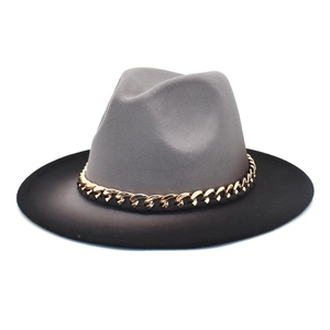 Détail du chapeau fedora bicolore gris et noir avec une chaîne dorée décorative chic