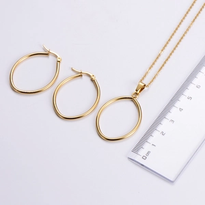 Detail of gold oval pendant necklace and earrings set with size measurements in cm