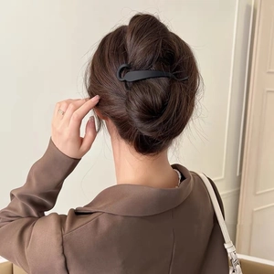 Elegant black minimalist hair claw clip for women's bun hairstyle on plain background
