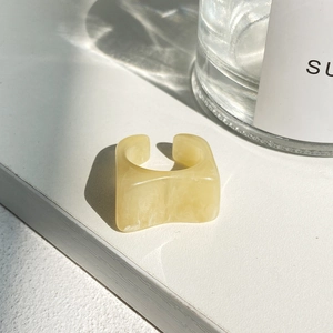 Detail view of a minimalist square resin ring with cream marble texture and adjustable open band