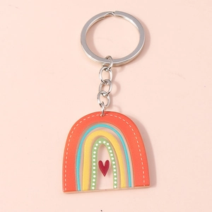 Detailed view of a colorful rainbow acrylic keychain with red heart on pink background