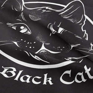 Close-up detail of a black cotton tapestry showing a white hand-drawn cat and lettering
