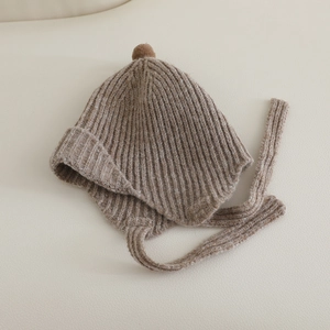 Détail du bonnet en tricot pour bébé avoine avec texture côtelée et pompon décoratif