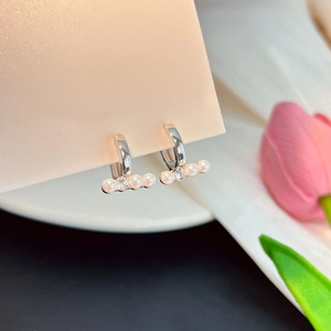Détail macro de boucles d'oreilles en argent avec quatre perles blanches et un cristal central