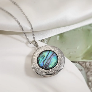 Natural abalone shell locket necklace on white silk background with silver chain