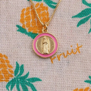 Macro view of gold-plated Virgin Mary necklace with pink enamel circular pendant