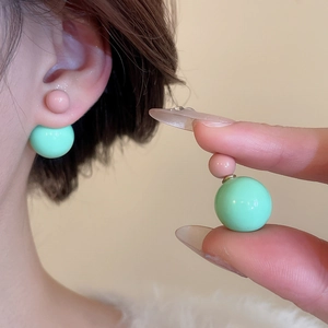 Detail of pink and mint green resin double ball earrings with shiny finish on ear