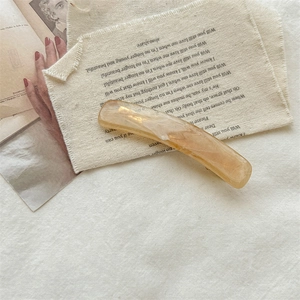 Close-up of translucent amber hair clip with marble texture on vintage paper background