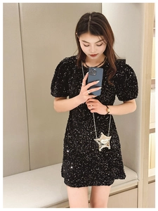 Detail of a silver star-shaped metal crossbody bag paired with a black sequin dress