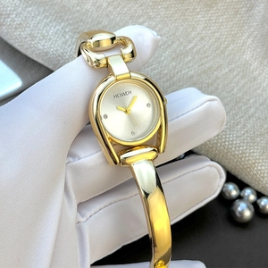 Detailed close-up of golden horsebit-style metal bracelet and oval dial on women's watch