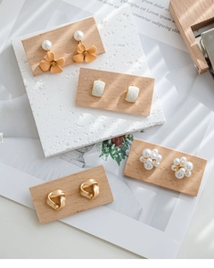 Detail of assorted earring set on walnut wood display including floral and pearl designs
