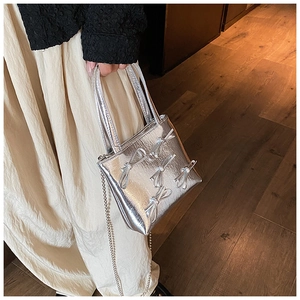 Detail of silver metallic handbag with 3D bow decorations and fine chain strap texture