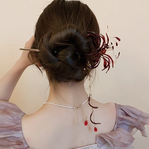 Detail of red Lycoris flower hair stick with gold tassels on an elegant updo