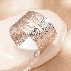 Detailed view of silver textured wide open bangle with a hollow cross center design
