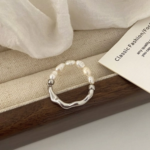 Detalle de anillo de perlas de agua dulce con banda de plata ondulada en soporte de lino