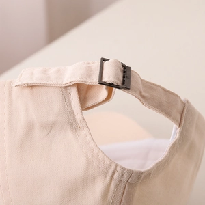 Détail de la boucle en métal réglable et du tissu en coton beige de la casquette