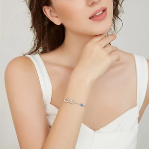 Elegant silver infinity bracelet with blue heart zircon stone on a model's wrist