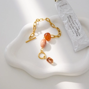 Detail of vintage gold chain bracelet with amber and marble-textured resin beads on ceramic