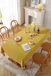 Detail of yellow cotton tablecloth with white lace edges on a wooden table setup