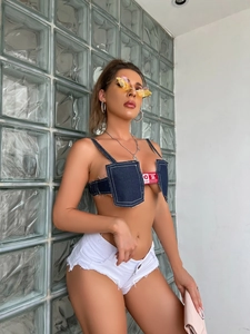 Scatto all'aperto di una donna in pantaloncini di jeans a vita bassa e top blu scuro