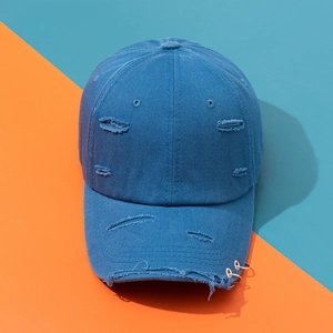 Distressed blue cotton baseball cap with ripped details and metal rings on brim
