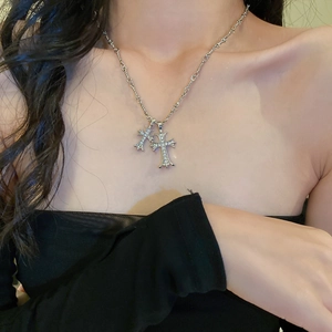 Detail showing a silver-layered double cross pendant necklace with sparkling rhinestones