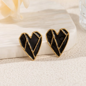 Detail of 18k gold heart-shaped stud earrings with black enamel on a stone base