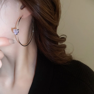 Gros plan d'un mannequin portant des créoles argentées en C avec zircon coeur violet